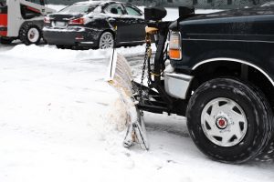 A car with a snow brush and shovel attached to the front.