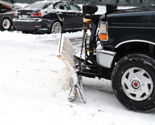 A car with a snow brush and shovel attached to the front.